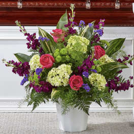 Pink roses and purple flowers arranged in a white vase