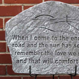 Engraved memorial stone with a quote against a brick wall.