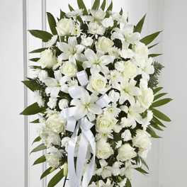 White floral standing spray with ribbon on a black easel