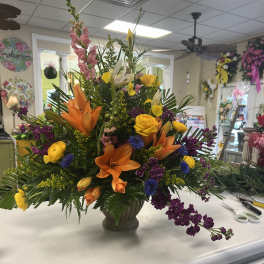 Large mixed flower arrangement in a vase with orange lilies and yellow roses