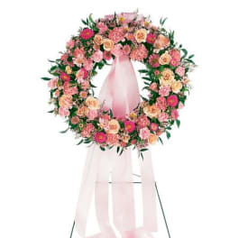 Pink and peach rose and carnation standing wreath with long pink ribbons on a metal easel