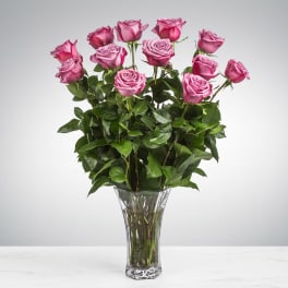 Tall arrangement of pink roses in a clear glass vase.