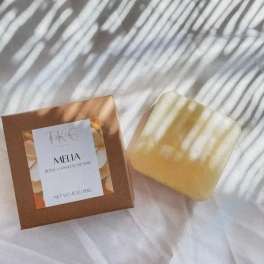 Boxed body and hand soap bar beside a translucent yellow soap bar