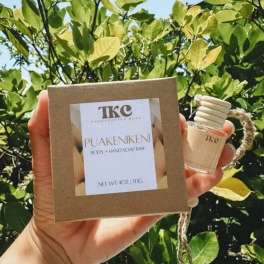 Hand holding a boxed soap bar and a small bottle outdoors
