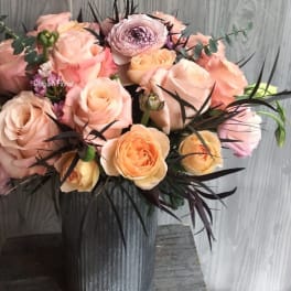Peach and blush roses in a tall metal vase