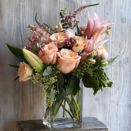 Peach roses and pink lilies in a clear glass vase