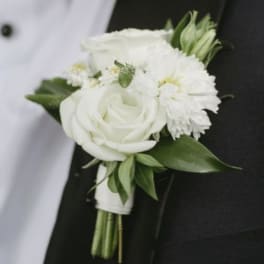 White rose and mum boutonniere pinned to a black tuxedo lapel