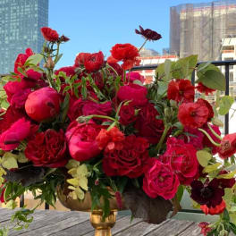 Red and pink floral arrangement in a gold pedestal vase