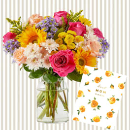 Mixed bouquet in a glass vase beside a "best mom ever" card