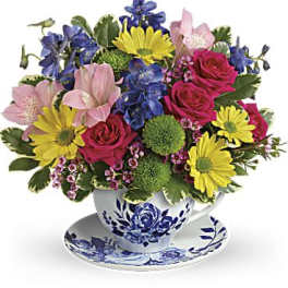 Colorful mixed flower arrangement in a blue and white teacup with matching saucer