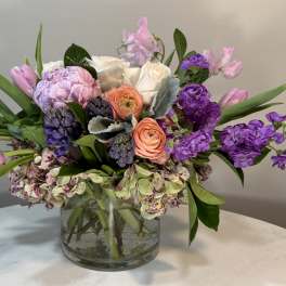 Mixed pink, purple, and white flowers in a clear glass vase