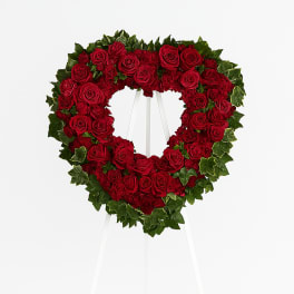 Heart-shaped wreath of red roses on a white easel