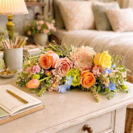 Low floral arrangement with roses, a chrysanthemum, and small blue flowers