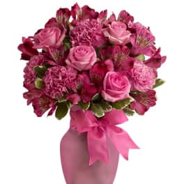 Pink rose and carnation bouquet in a pink vase with a ribbon
