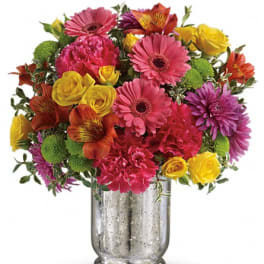 Colorful mixed bouquet in a silver vase with pink, yellow, orange, and purple blooms