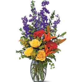 Mixed bouquet of purple, yellow, orange, and red flowers in a glass vase