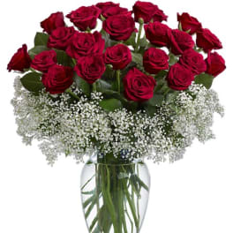 Red roses arranged in a clear glass vase with white baby's breath