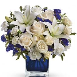 White roses and lilies arranged in a blue glass vase