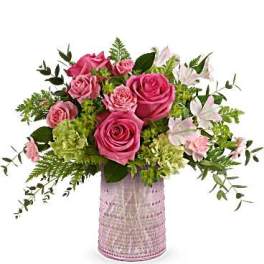 Pink roses and white lilies arranged in a pink vase