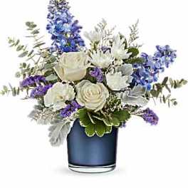 White and blue floral arrangement in a blue glass vase