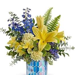 Yellow lilies and blue flowers in a mosaic glass vase
