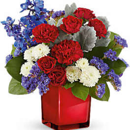 Red roses, white carnations, and blue flowers in a red vase