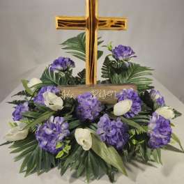 Purple and white floral arrangement with a gold cross centerpiece
