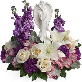 White angel figurine surrounded by purple and white flowers