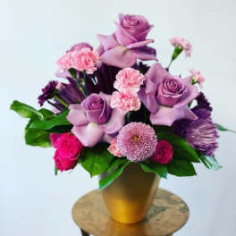 Purple and pink floral arrangement in a gold vase