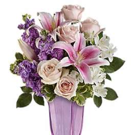 Pink lilies and roses in a purple vase with white filler flowers