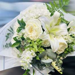 White bouquet with lilies, roses, and hydrangea wrapped in paper