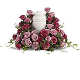 Pink and burgundy roses arranged around a white urn