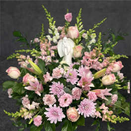 Pink and white floral arrangement with a small angel figurine in the center