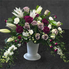 White lilies and mauve roses in a white pedestal vase