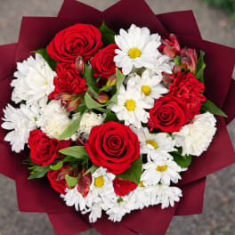 Bouquet of red roses and white daisies wrapped in burgundy paper