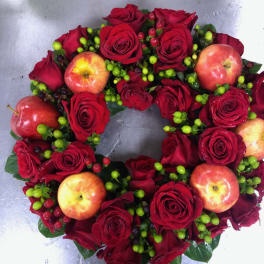 Heart-shaped arrangement of red roses with apples and berry accents