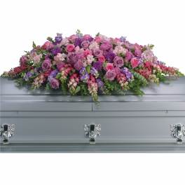 Lavender and pink casket spray of roses and mixed flowers displayed on a silver casket
