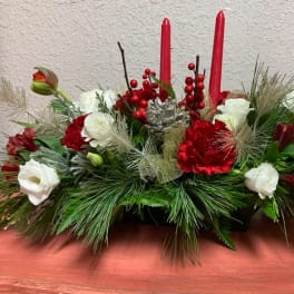 Low holiday centerpiece with red and white flowers and two red candles