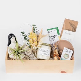 Gift basket with a small floral bundle, candle, tea, incense, and a plant figurine