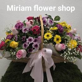 Basket arrangement of pink, purple, yellow, and red flowers with a pink ribbon