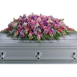Pink and purple floral casket spray on a gray casket