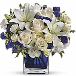 White lilies and roses arranged in a blue glass vase
