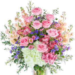 Pink roses and mixed blooms arranged in a clear glass vase