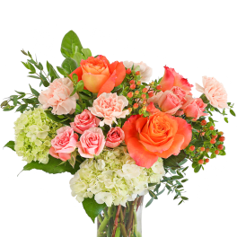 Bouquet of orange and pink roses with pale hydrangeas in a clear glass vase