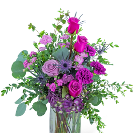 Purple and pink flower arrangement in a clear glass vase