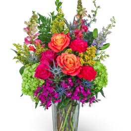 Bright mixed bouquet in a clear glass vase with roses and carnations