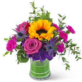 Colorful bouquet with a sunflower, pink roses, and purple flowers in a striped glass vase