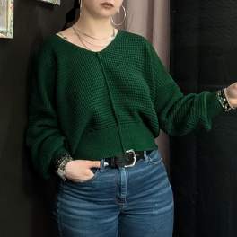 Person wearing a dark green sweater and blue jeans