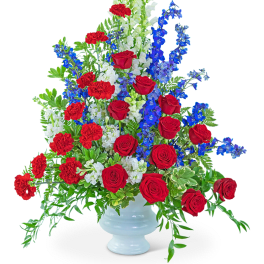 Red roses, red carnations, and blue flowers in a white vase