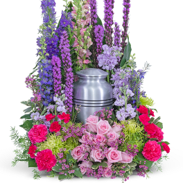Tall floral arrangement around a silver urn with pink and purple flowers